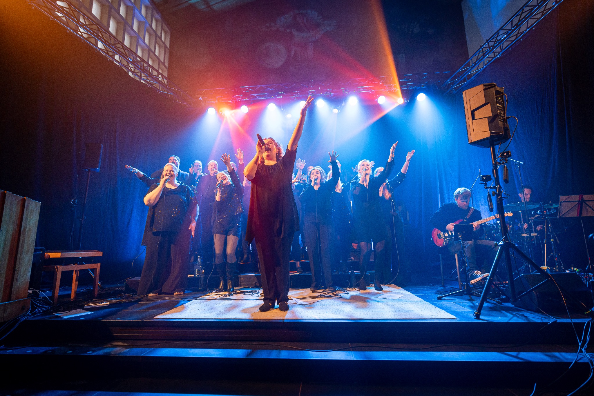Voices of Worship und Band auf der Bühne im blauen und orangefarbenen Konzertlicht